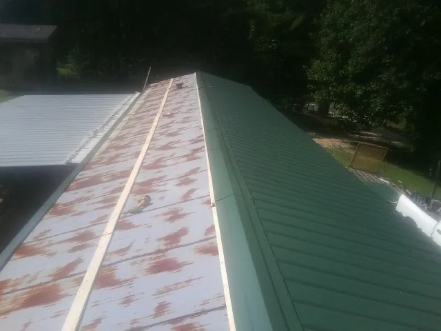 Old rusted panels beside newly installed green metal roofing — Wind Damage Roof Repair by Roofing Brothers in Amsterdam