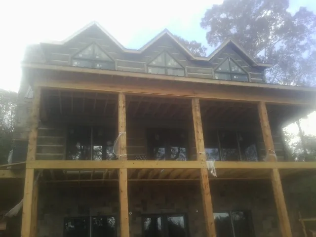 Dormers and porch framing on a large log home under construction — Roof Coating work by our crew in Amsterdam
